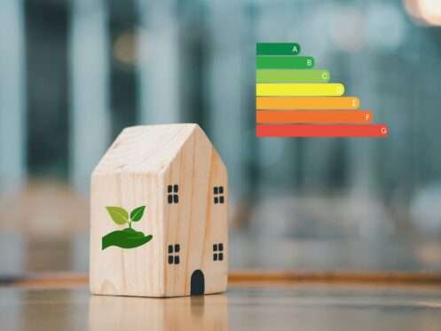 Wooden toy house next to an energy efficiency rating scale ranging from A to G