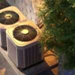 Overhead view of two residential HVAC systems or air conditioning condenser units next to a brick wall, emphasizing the importance of regular maintenance and cleaning for efficient cooling in California.