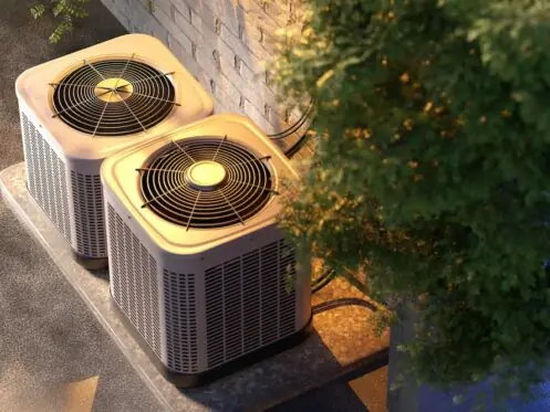 Overhead view of two residential HVAC systems or air conditioning condenser units next to a brick wall, emphasizing the importance of regular maintenance and cleaning for efficient cooling in California.