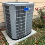 Close-up of a modern outdoor HVAC unit used for central air cooling in a suburban residential setting.